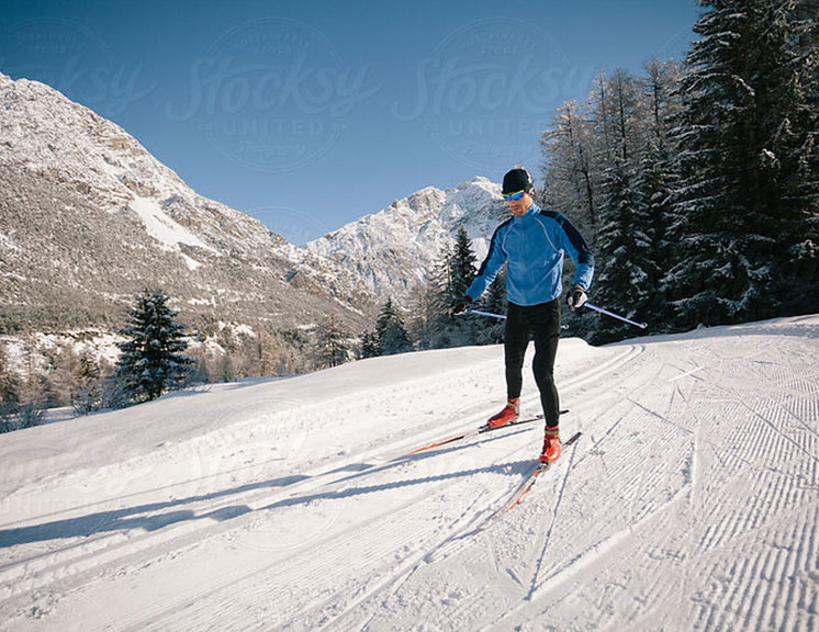 Man with blue and black jacket cross country skiing