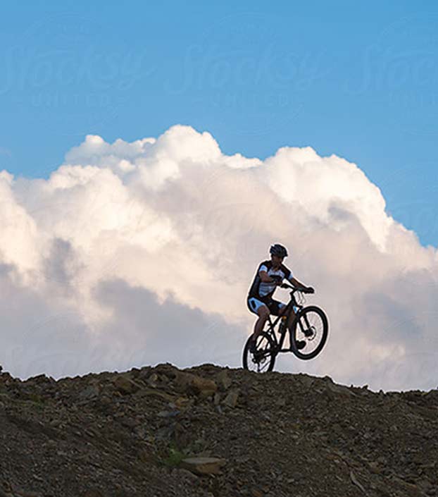 Mountain biker on one wheel on hillside