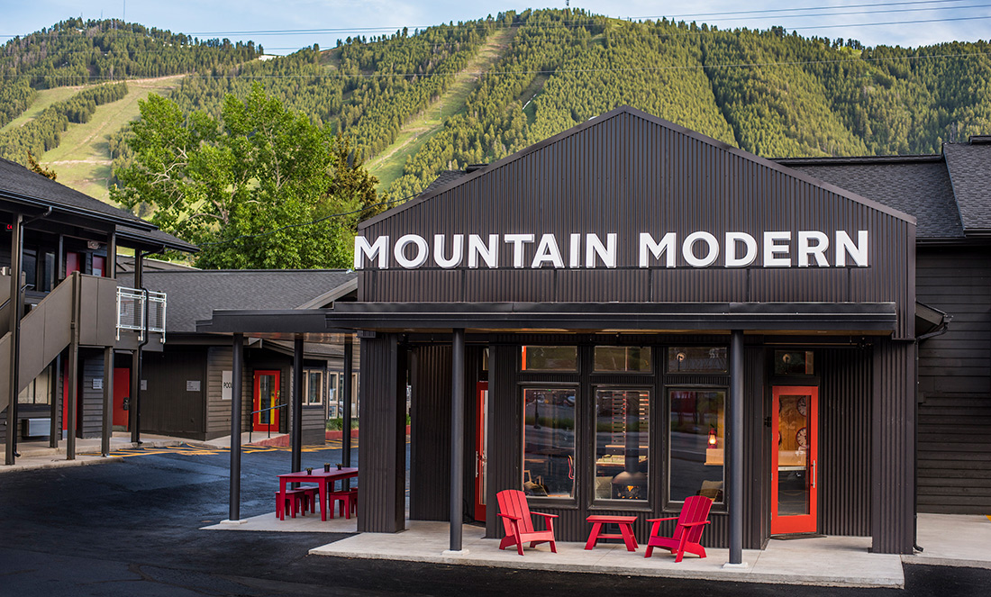 Mountain Modern Motel exterior in the summer with red Adirondack chairs and table