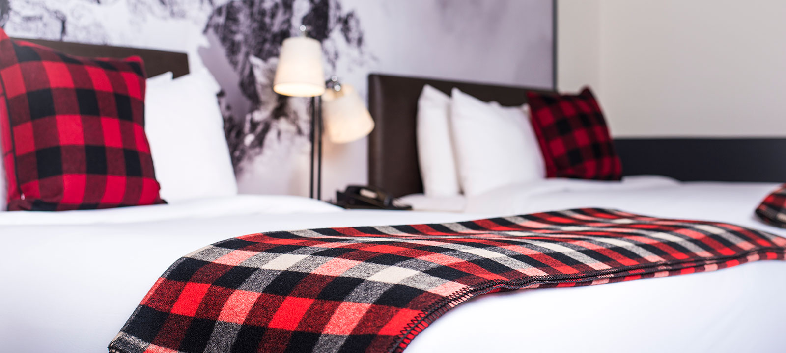 Mountain Modern Motel bed with red, black, and white plaid blanket