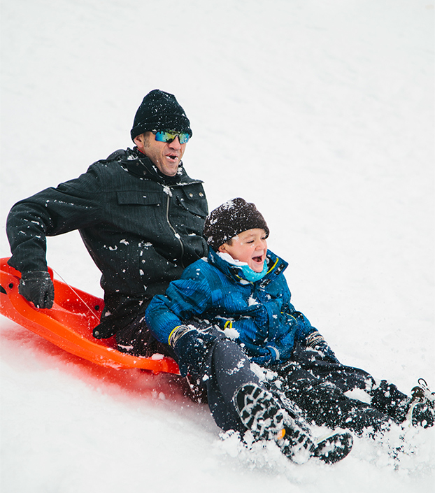 Man and boy sledding down a hill ready to fall off the sled