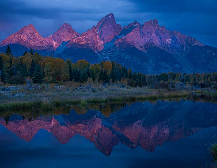 Grant Teton National Park purple mountains reflected in the mountain lake during the fall