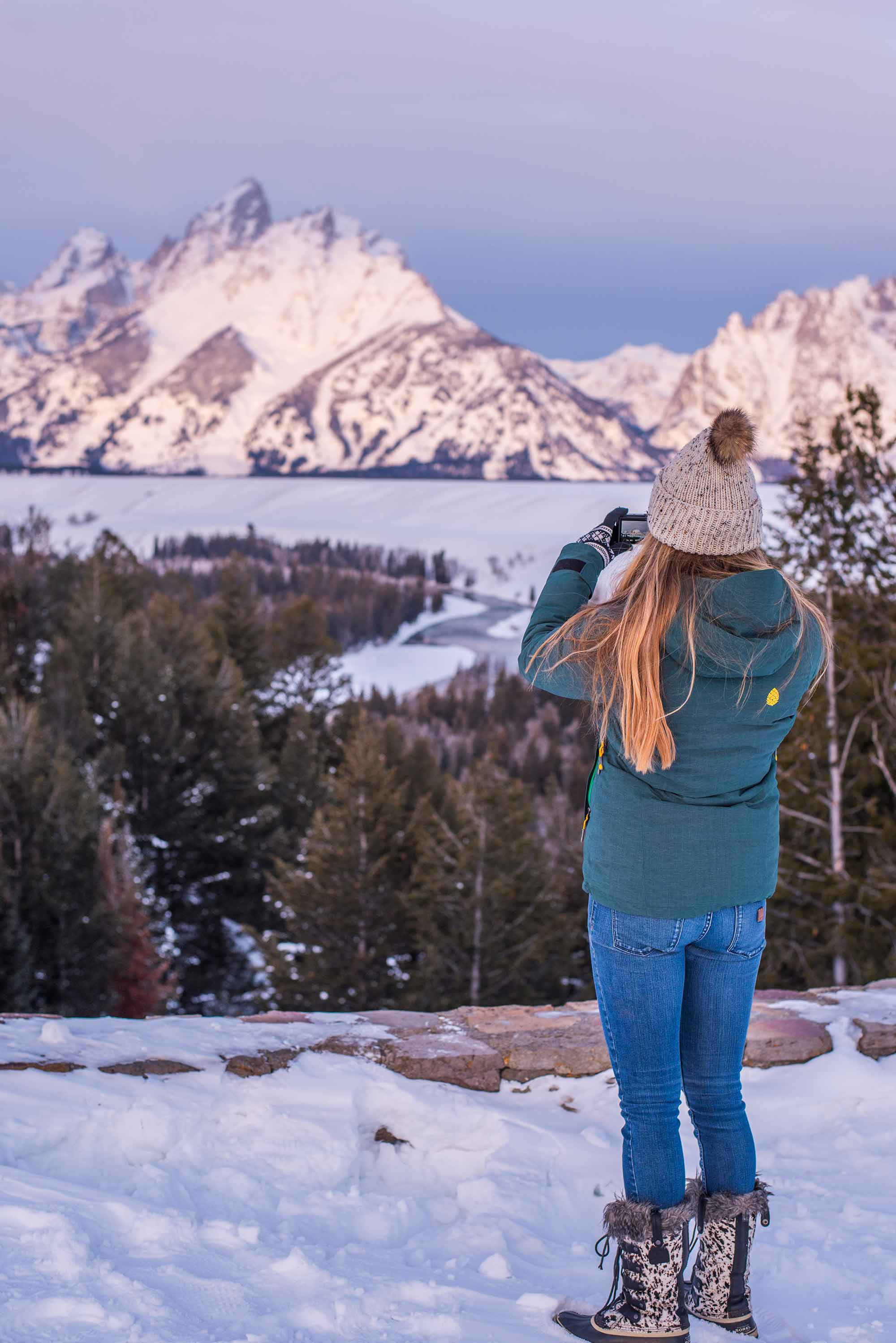 Woman taking picture of Grand Tetons in winter