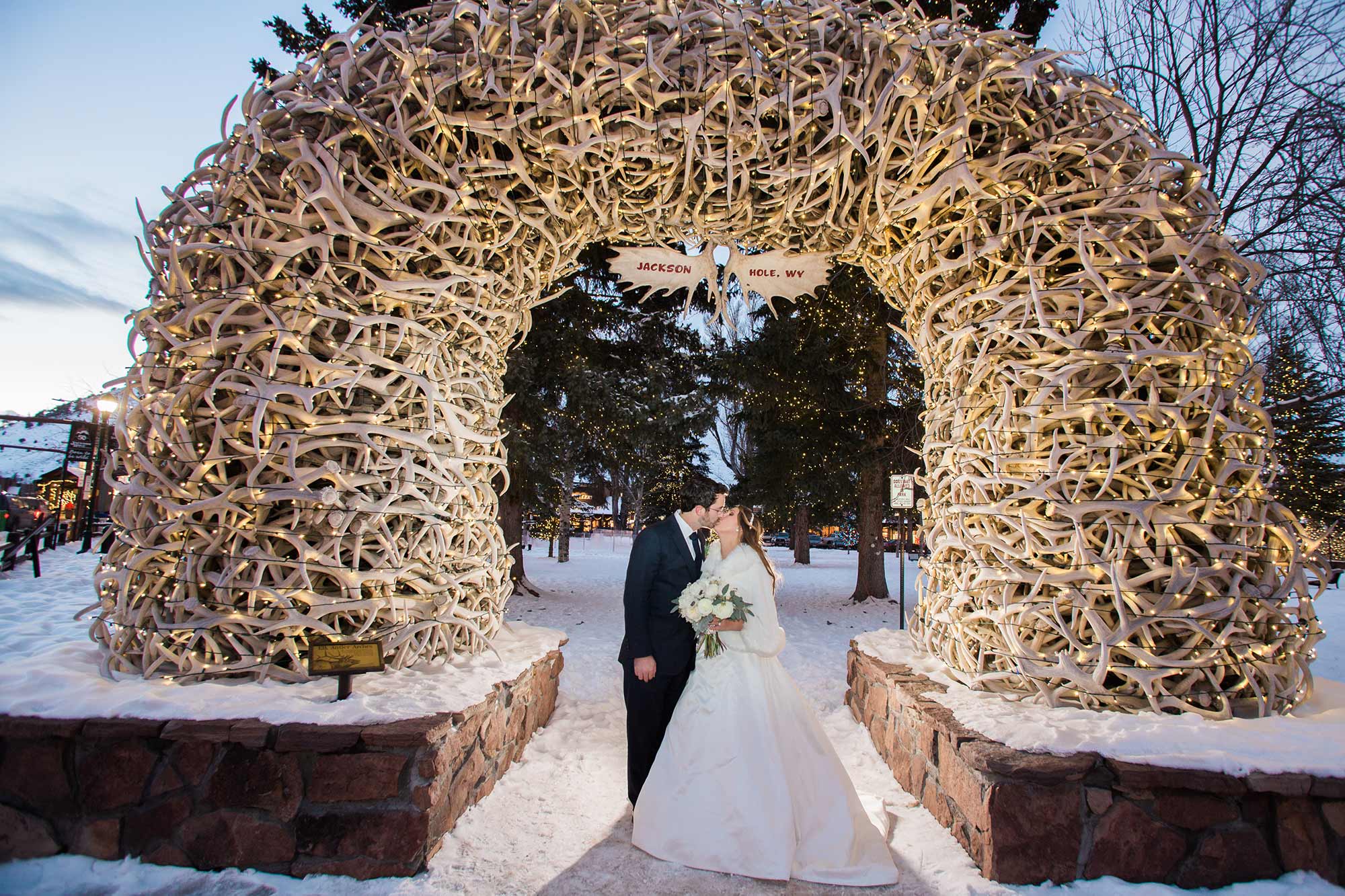 Winter-Wedding-in-Jackson under Town Square antler arch with white lights and snow