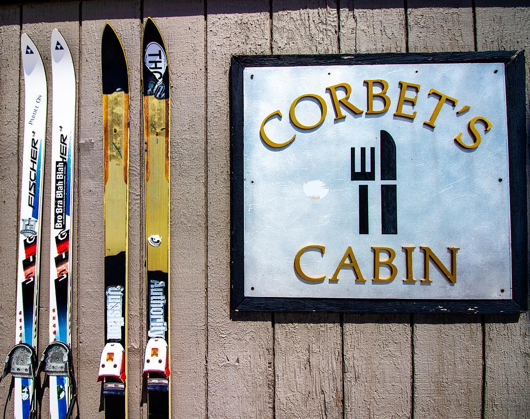 Corbet's Cabin sign outside of restaurant with skis hanging next to sign