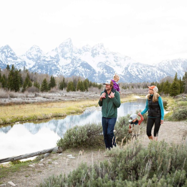Couple walking with kids along mountain stream with white capped mountains