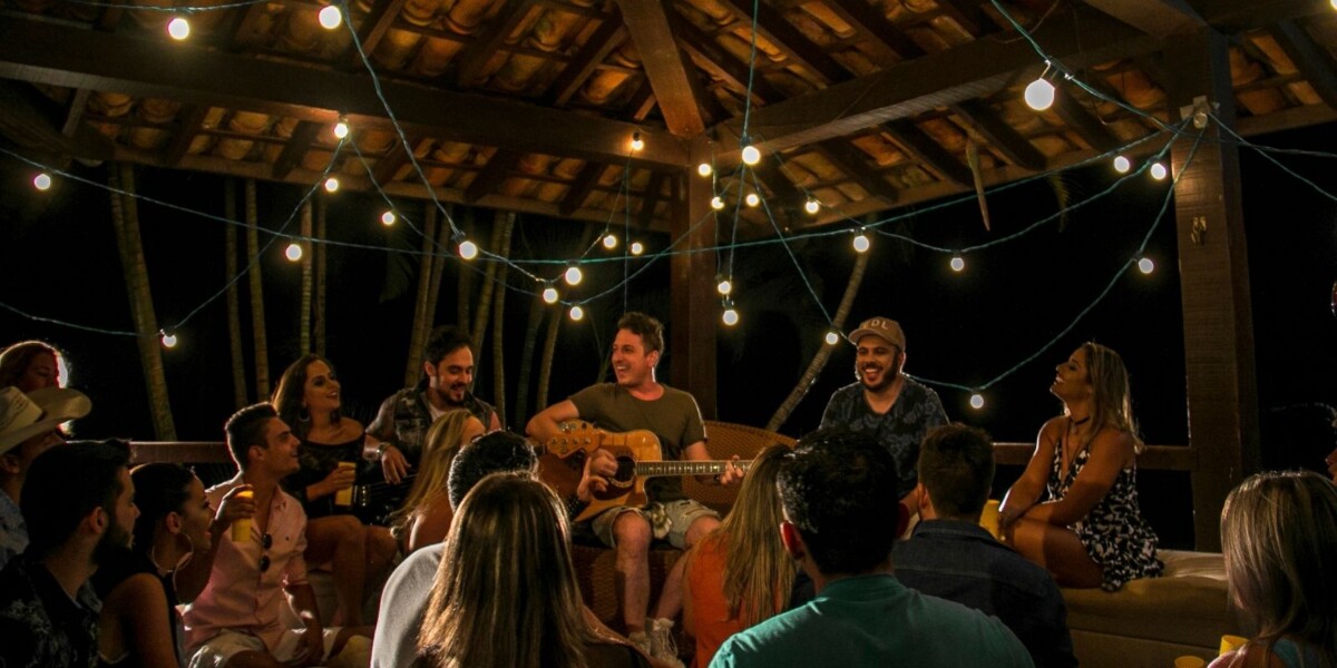 Crowd of people listening to three musicians under lights.